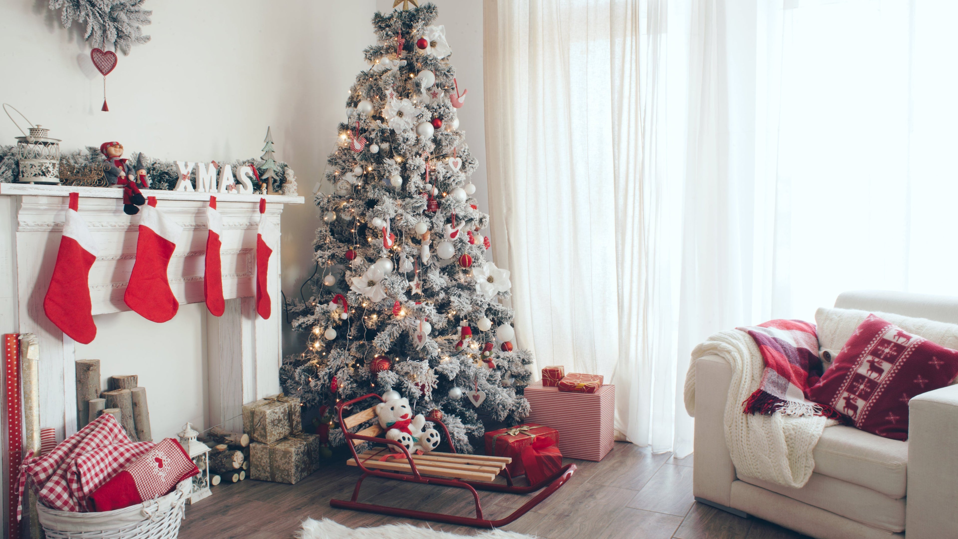 Decorated Christmas tree in a living room with stockings, presents, and a sleigh.