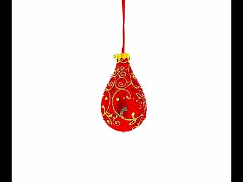Adorno navideño de cristal con flores doradas sobre remate de gota de agua roja