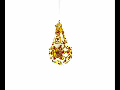 Adorno de cristal en forma de pera con joyas rojas sobre hojas doradas