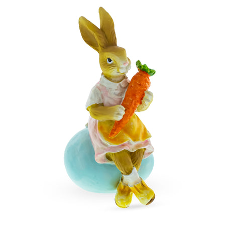 Springtime Serenity: Mother Bunny Cradling Carrot Atop a Decorative Easter Egg Figurine in Multi color,  shape